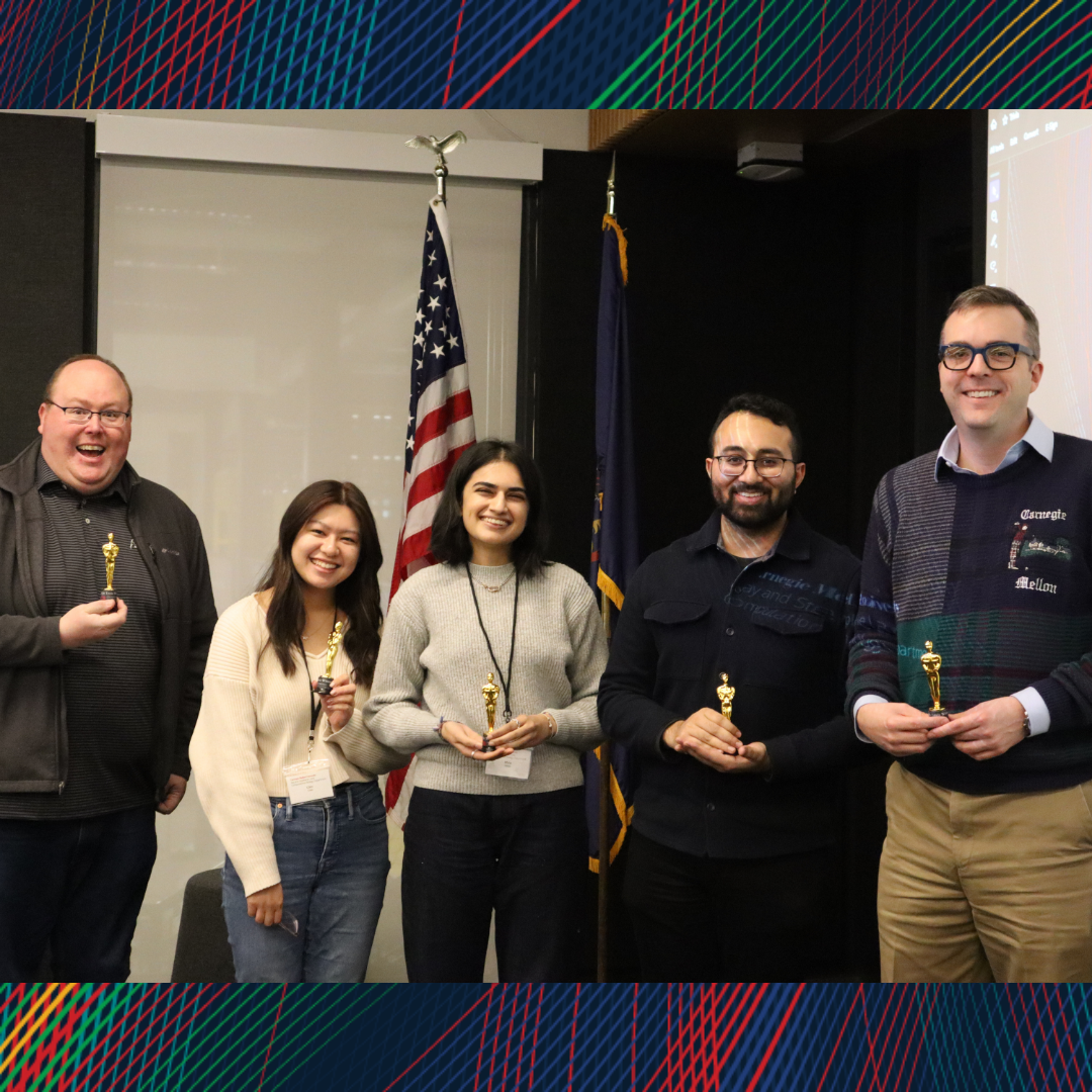 A group of people smiling at the camera with trivia trophies