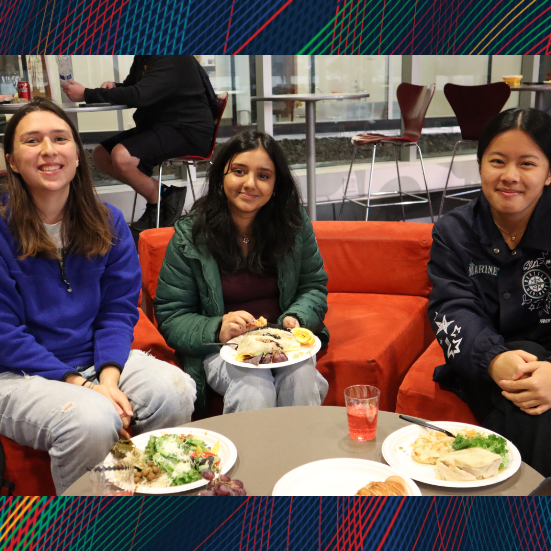 Three women sitting on the couch at dinner smiling at the camera