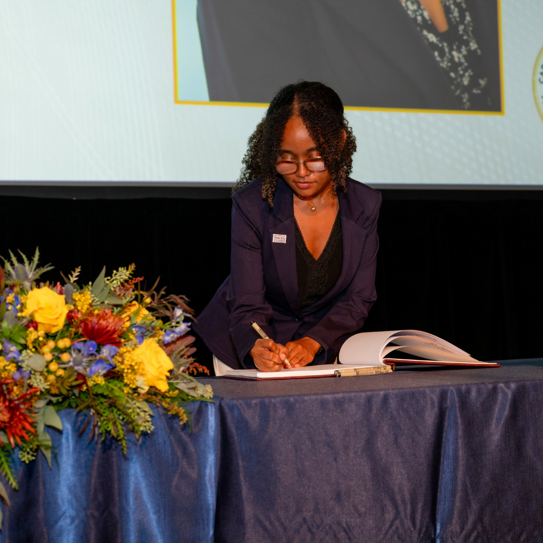A woman signs a book at the CMU Rales Fellowship ceremony