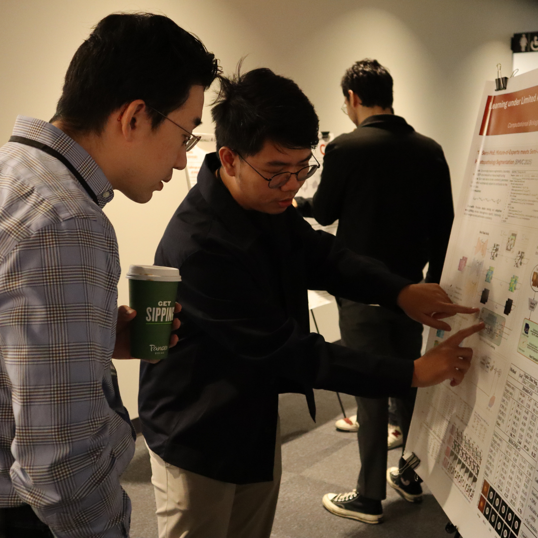 A man pointing at a research poster and discussing with another man