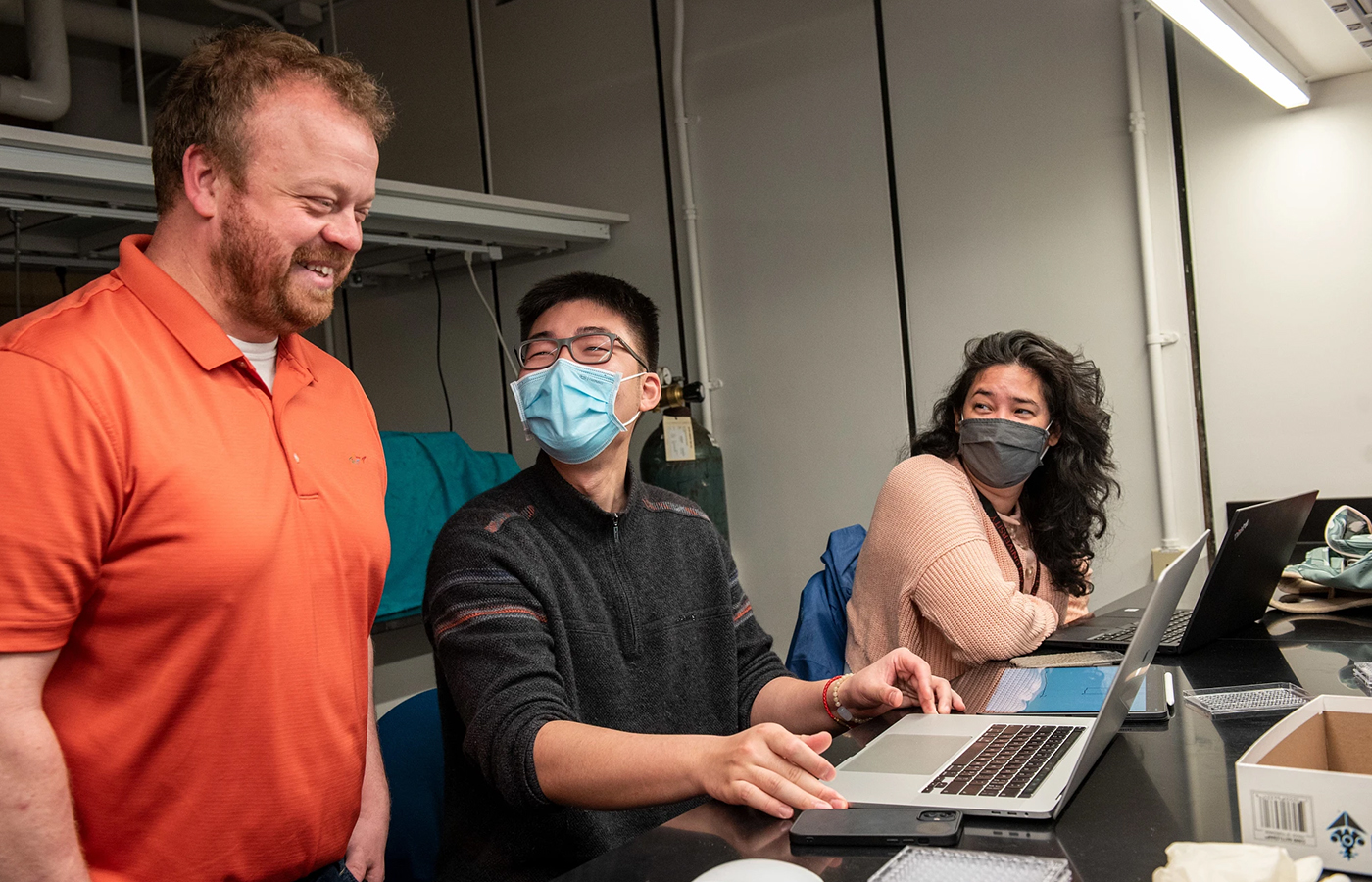 Joshua Kangas teaching two students sitting at a desk on their laptops