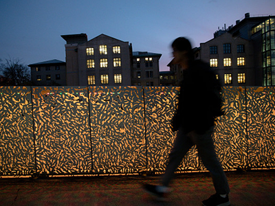 student walking across a lit bridge at night