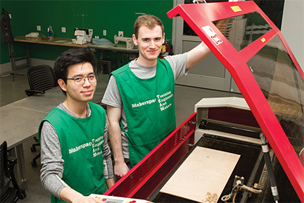 Benjamin Lawson (right) and Brian Lee (left) use laser cutter to create trusses