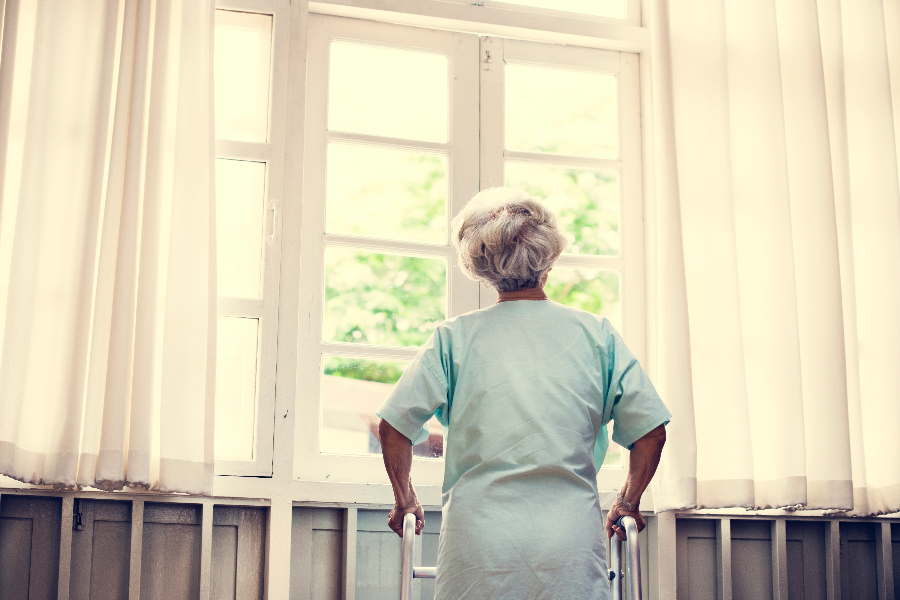 elderly woman looking out sunny window