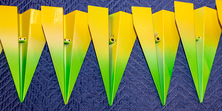 Photo of rows of the planes: green and yellow. Shows the parts where the plane articulates with the suspension pieces.
