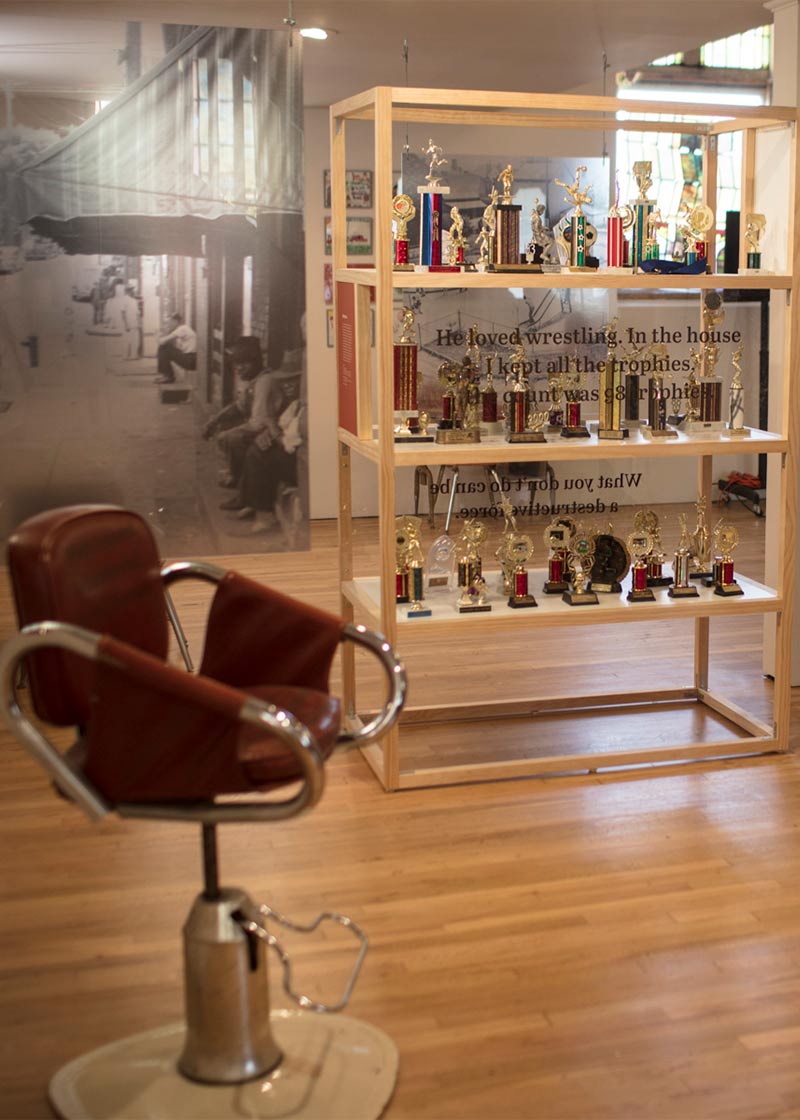 Old leather barber's chair and a bookcase full of athletic trophies.