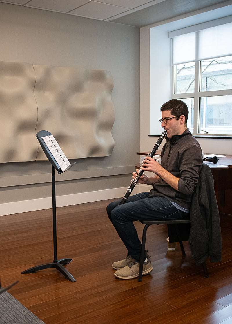 Photo of a student in a practice room playing clarinet.