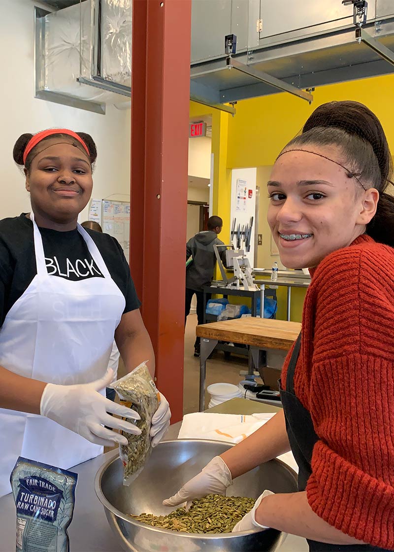 Two young women mixing ingredients, smiling.