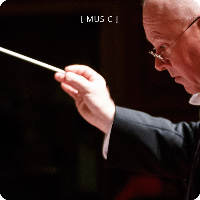 dramatically-lit conductor holding a baton