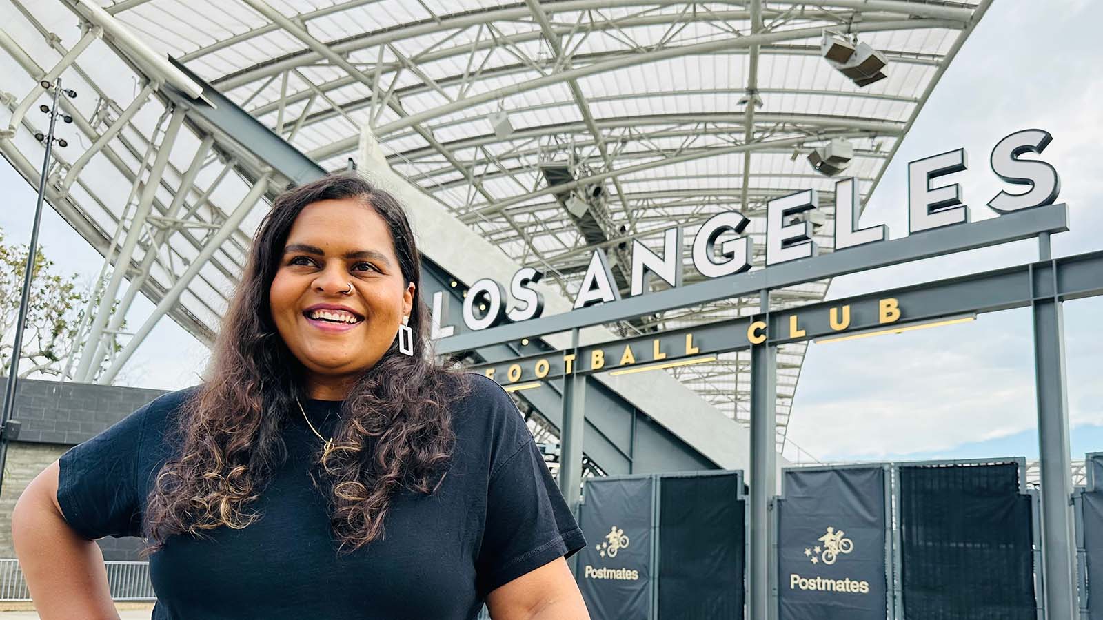 Divya Joseph standing in front of a stadium.