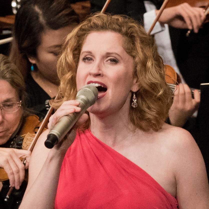 Close up of Christiane Noll singing in front of an orchestra.