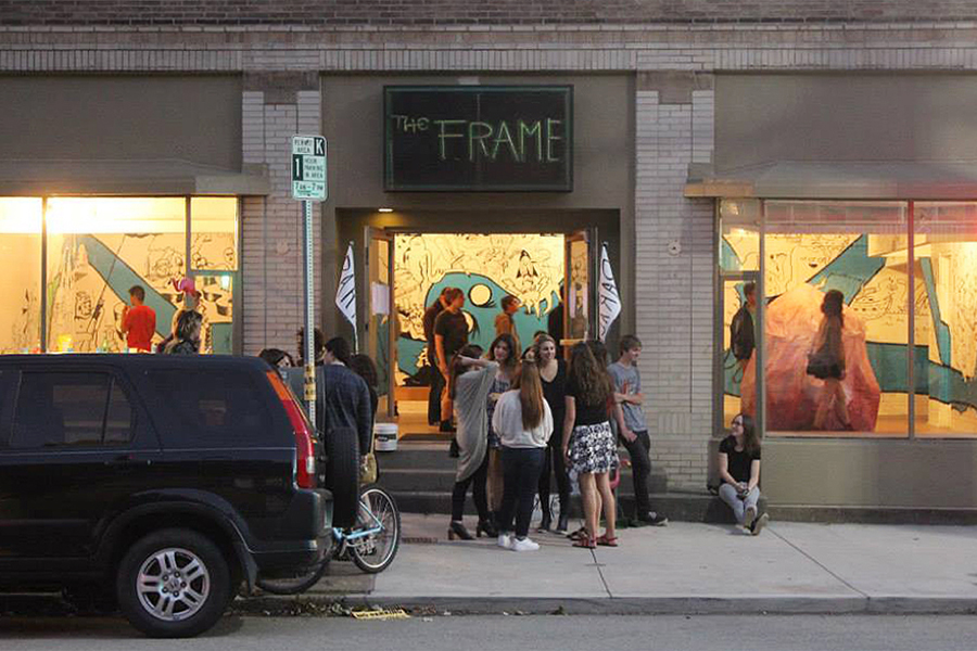 Students entering The Frame from the sidewalk; the gallery is full of students.