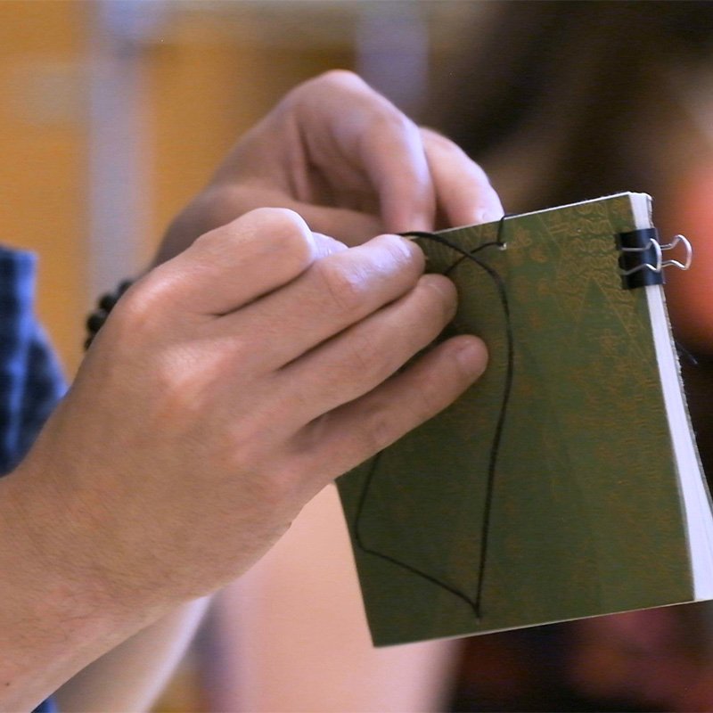 Hands as they bind a book.