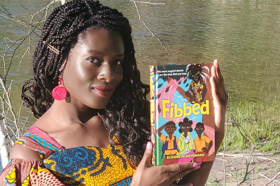 Elizabeth Agyemang showing off the cover of her first published book, Fibbed.