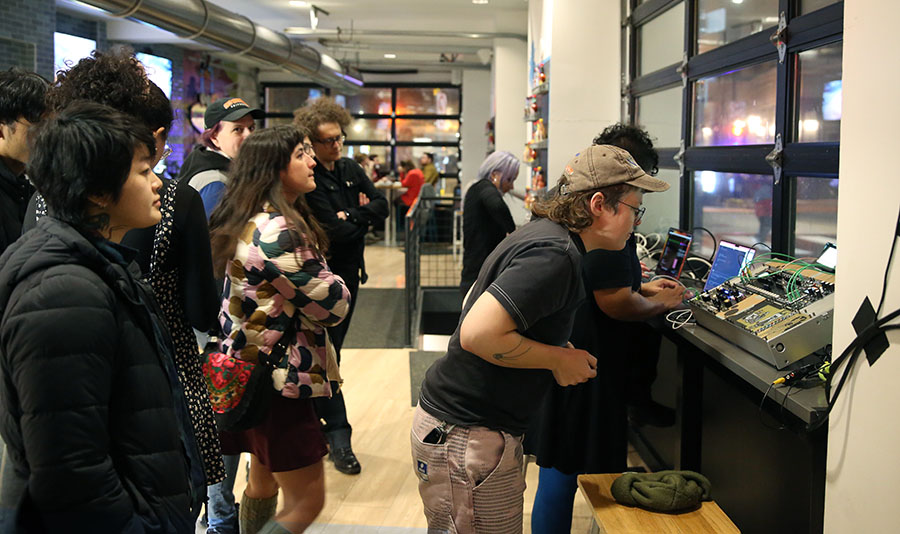 A group of people observing computers and electronics equipment