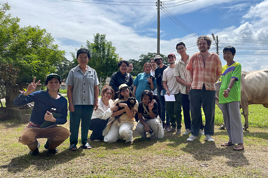 A group of people posing for a photo in bright sunlight while standing on grass