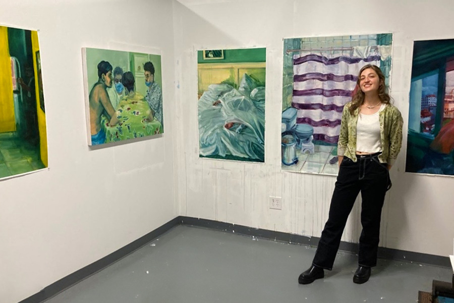 Ella Hepner posing against a background of artwork on the wall