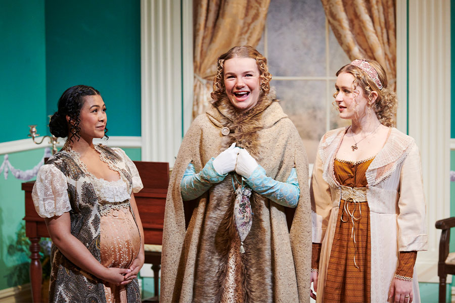 A smiling trio of theatre performers on stage