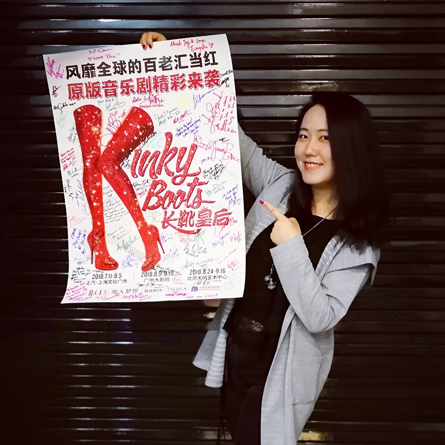 photo of Minfeng Zhang holding a Kinky Boots poster