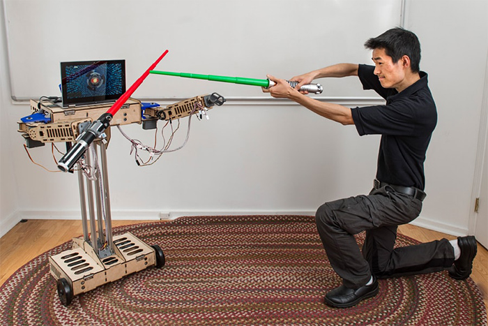 John Choi dueling with light sabers against a robot he made.