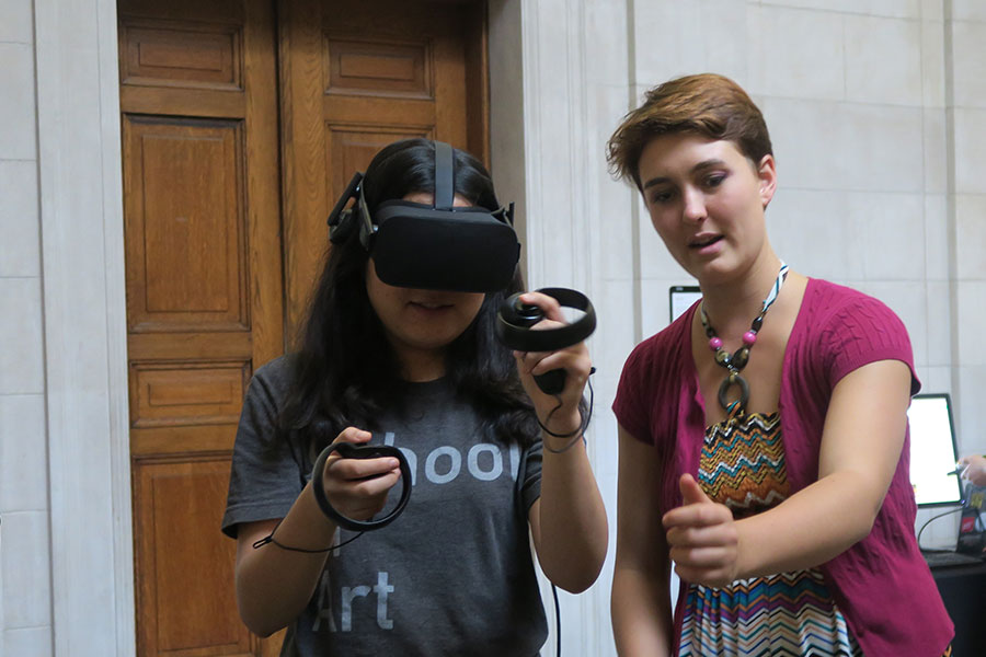 Students at a BXA showcase with virtual reality headset and controllers.