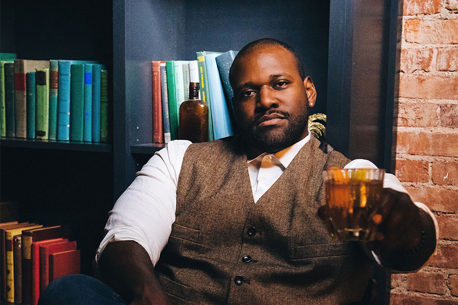 Photo of Cecil, relaxing in a lounge chair, toasting the camera with one of his mixed drinks.