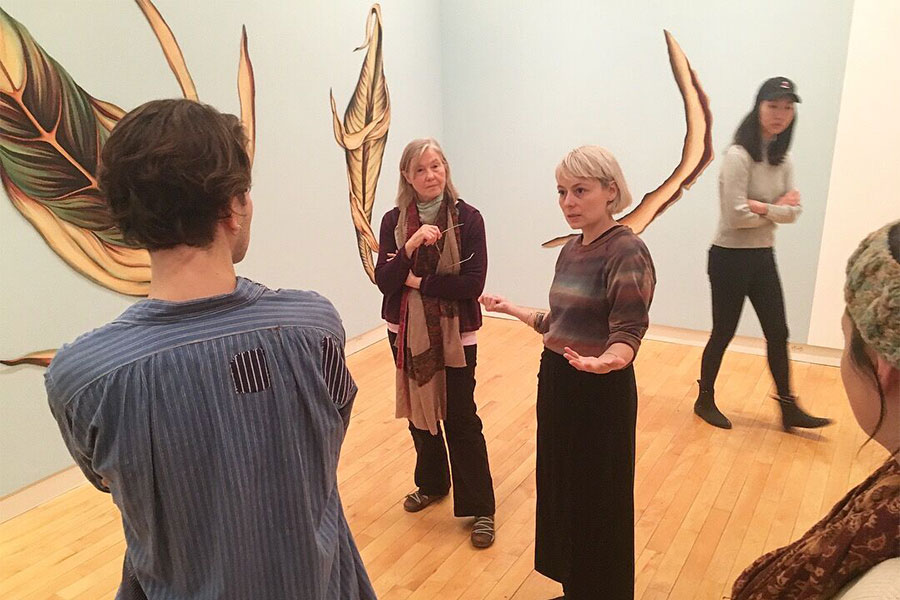 Photo of artist Faith Wilding talking to those at her gallery exhibition.