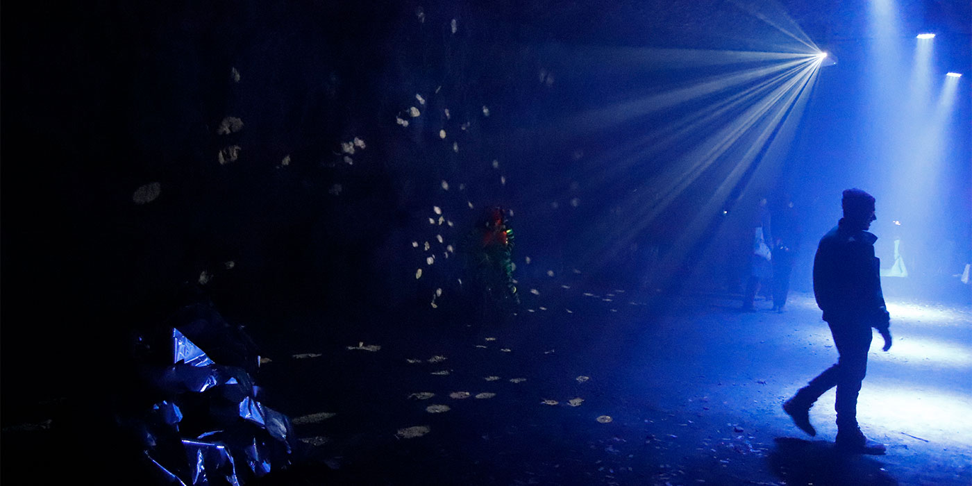 Photo of the limestone mine in blue lights, with the silhouette of a person walking away from the camera.