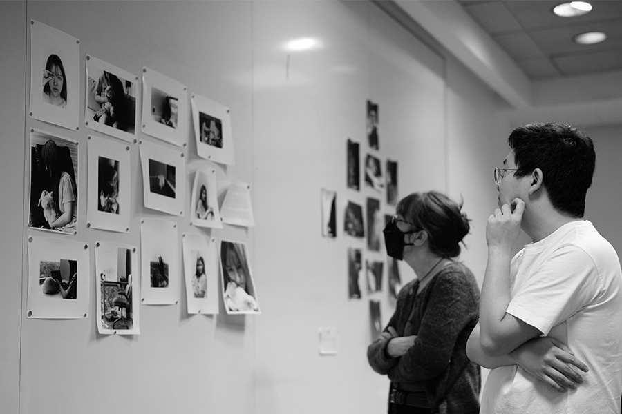 Two students, looking at a collection of pinned and printed photography.