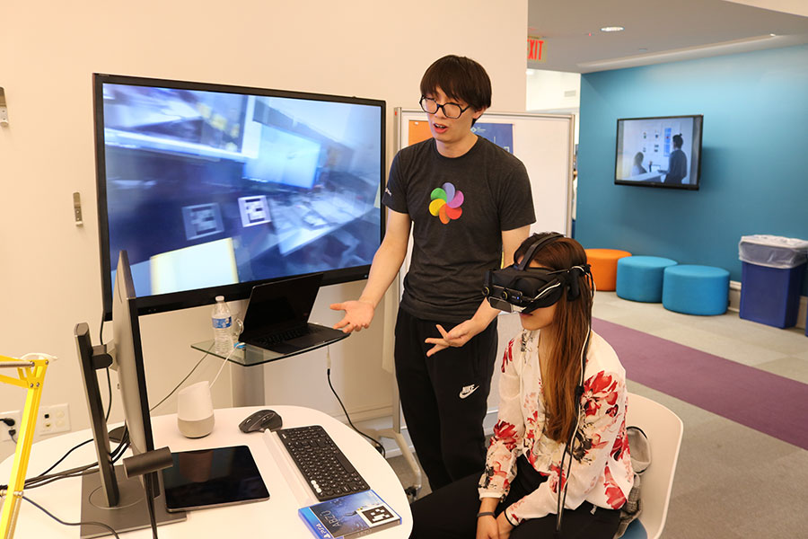 Photo of a student wearing a VR headset, interacting with another student.