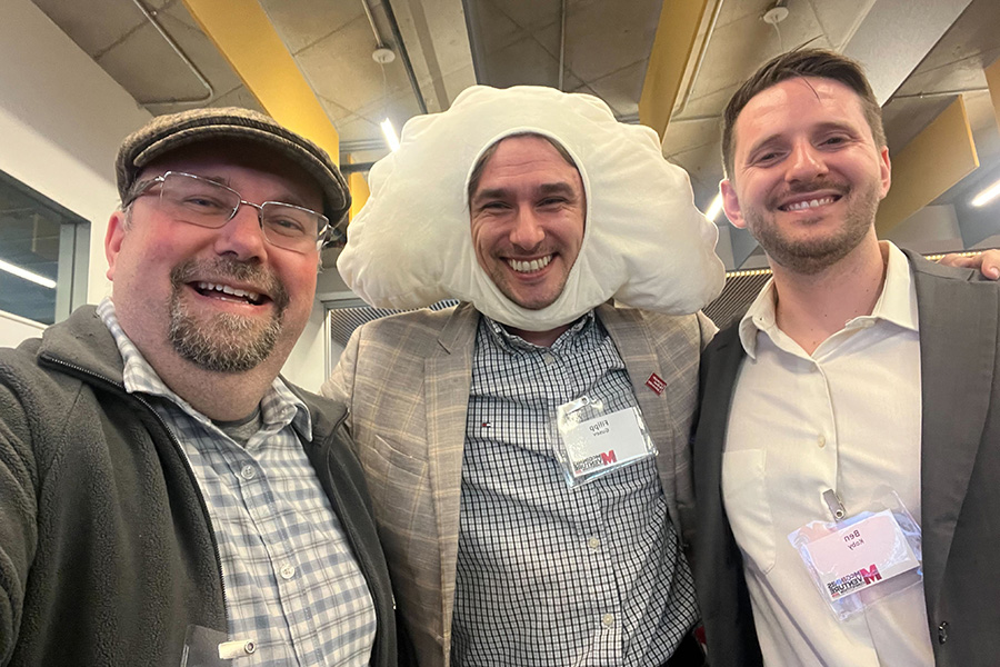 Filipp Gusev is wearing a pierogi headpiece, and he stands between Olexandr Isayev and Ben Koby.