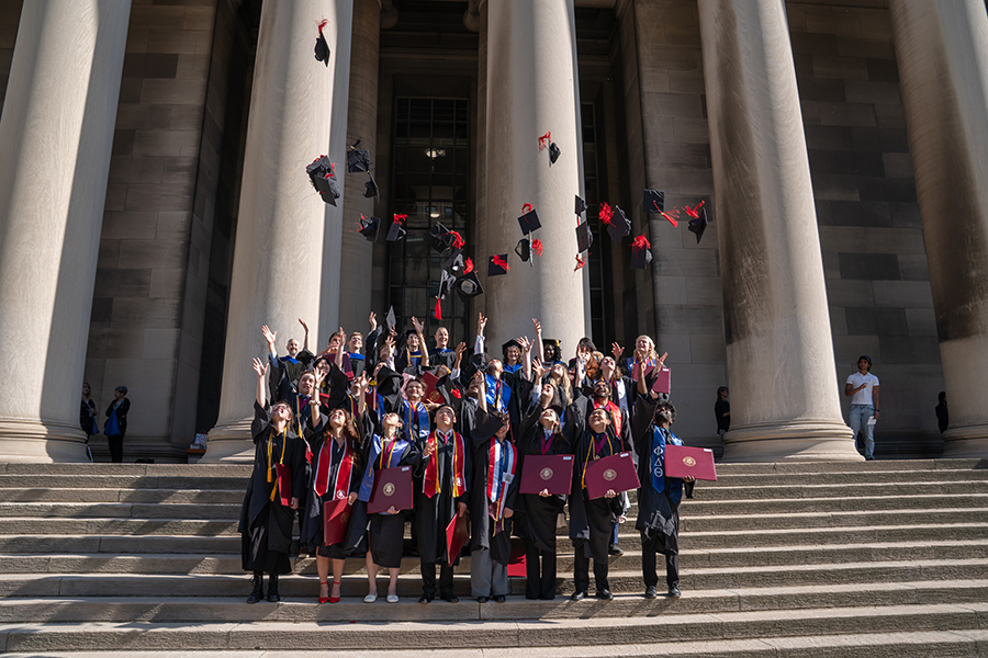 Chemistry graduates tossing caps in front of Mellon Institute