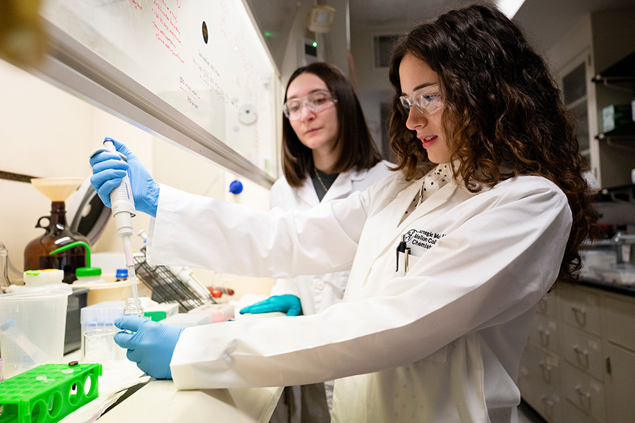 two students wearing goggles in a lab setting