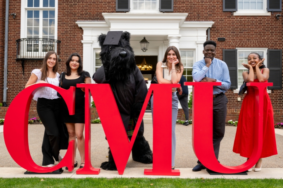 Alessandra Handrinos with college friends standing behind the giant CMU letters.
