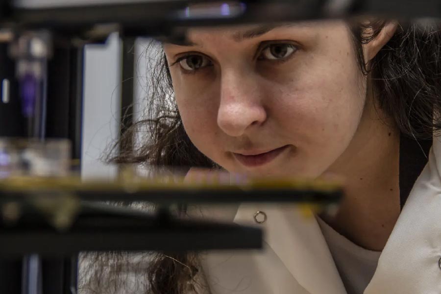 An image of Victoria Webster-Wood, an assistant professor of mechanical engineering at CMU, working with lab equipment.