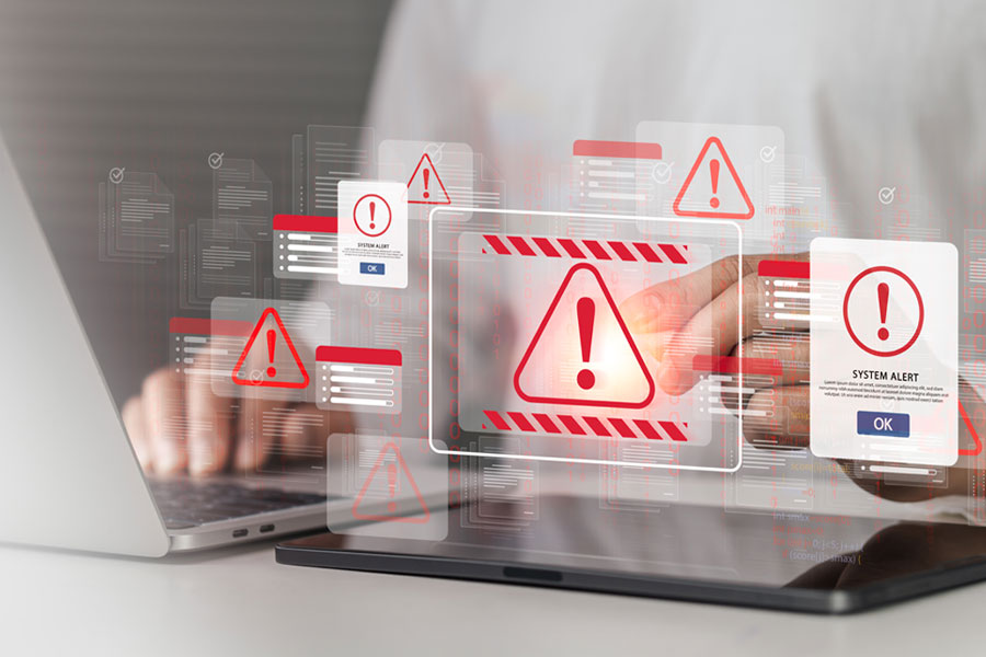 Person using a laptop with overlaid digital security alerts, warning symbols, and system notification windows.