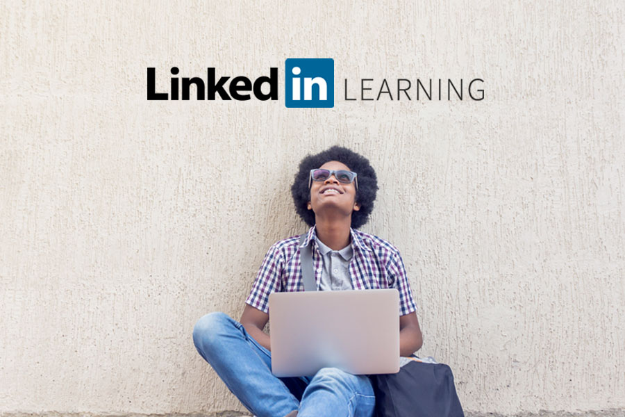 Man sitting against a wall and holding a laptop.