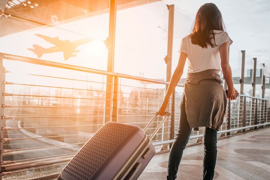 Student walking away rolling a piece of luggage.