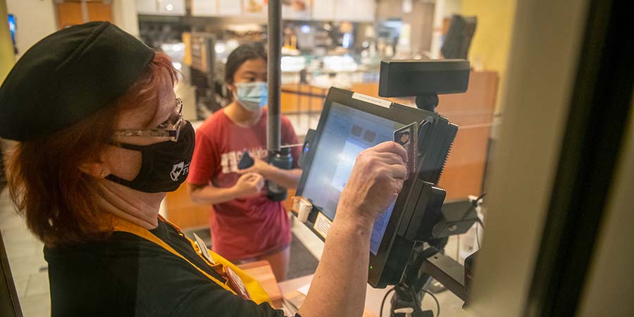 Pictured is a CMU dining staff member and CMU student paying for food.