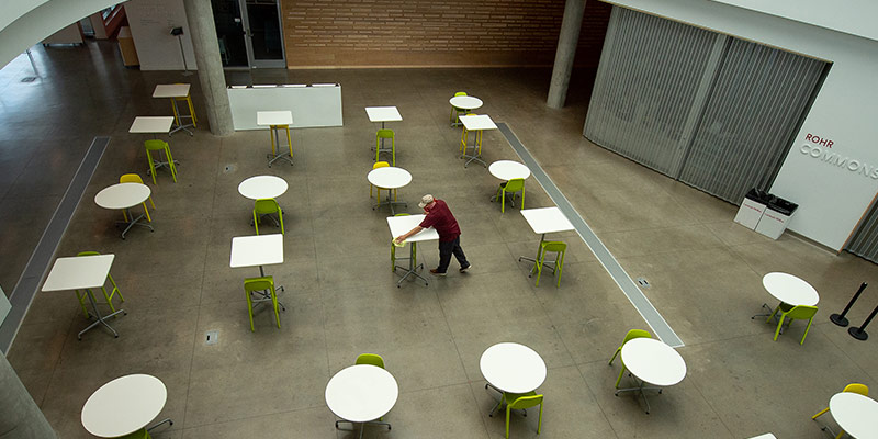 Photo of a man wiping down cafe tables in the Rohr Commons dining area.