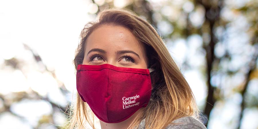 CMU students wearing masks and walking outside on campus among the fall leaves
