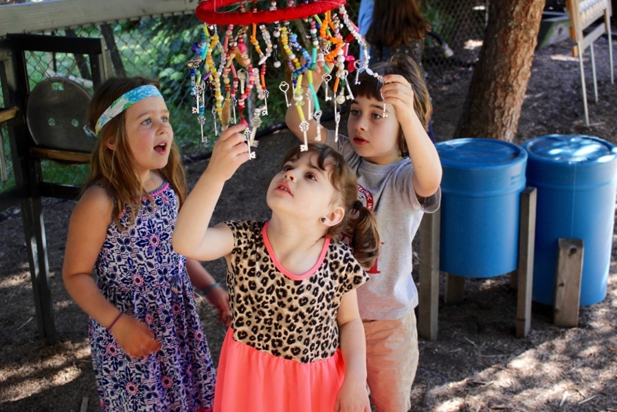Children touching a colored bead chandelier