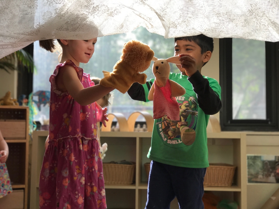 Two children putting on a puppet show