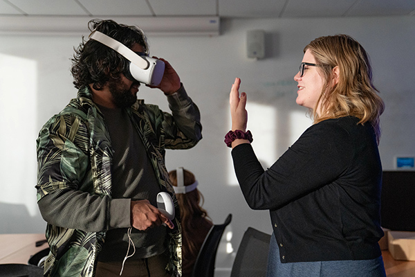 A student tests a virtual reality headset while another watches.