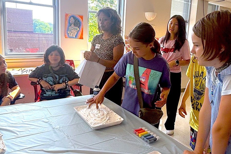 A middle school student finger paints