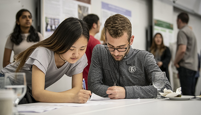 Two students examine a document spread on a table.