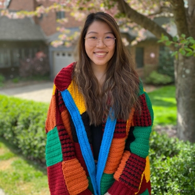 Natalie Hon in colorful cardigan by a tree