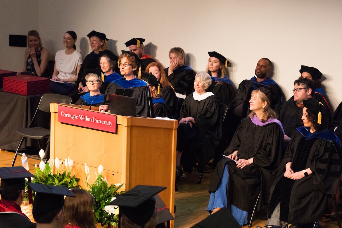 Woman in graduation robes gives a speech