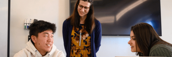 Two students and a professor engage in class discussion