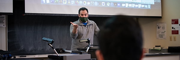 a teacher at the front of the class at a podium